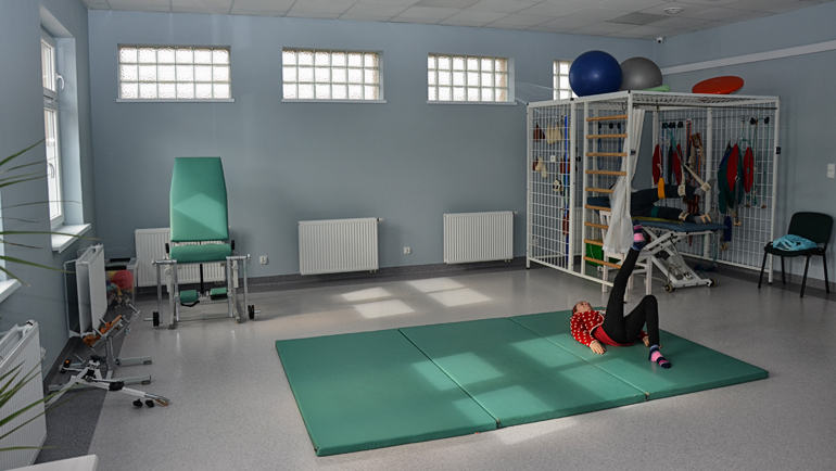 sala rehabilitacyjna i osoba ćwicząca na materacu