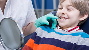 uśmiechnięte dziecko na fotelu dentystycznym